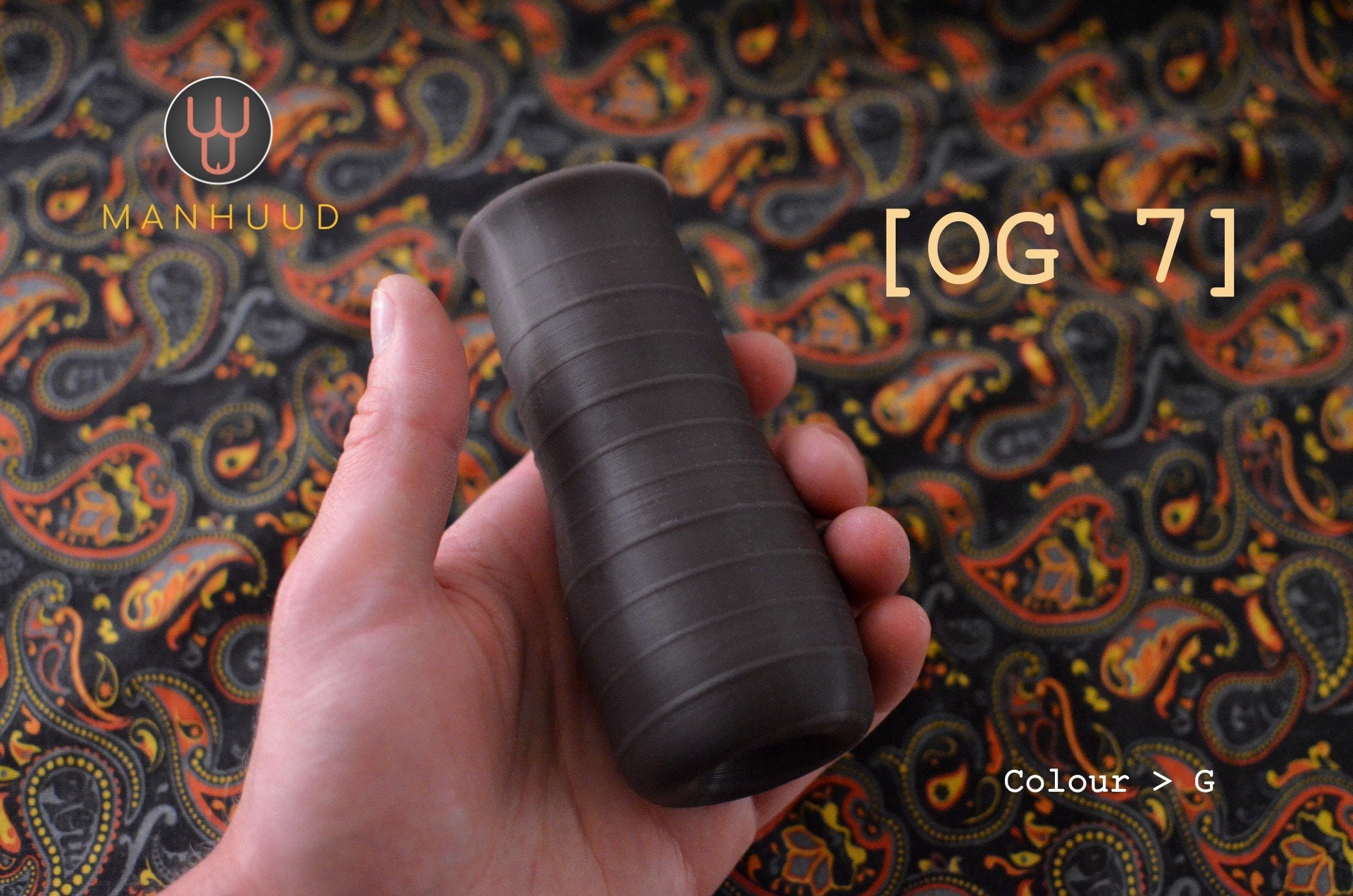 A hand holding a black textured cylinder against a paisley background
