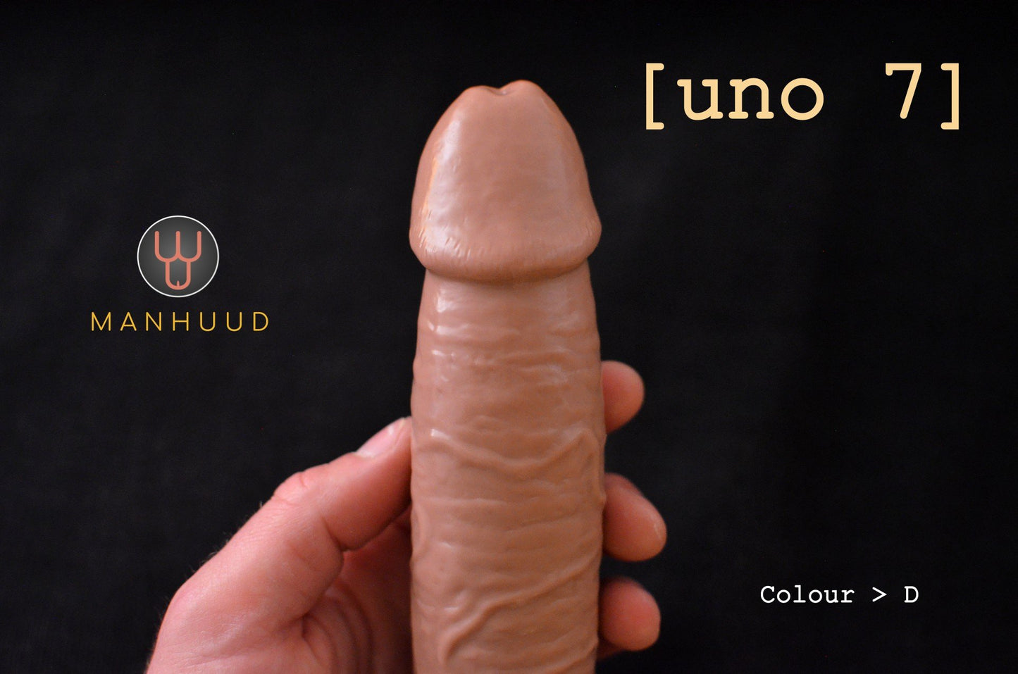A hand holding a MANHUUD "uno 7" silicone penis sleeve, showing realistic detail