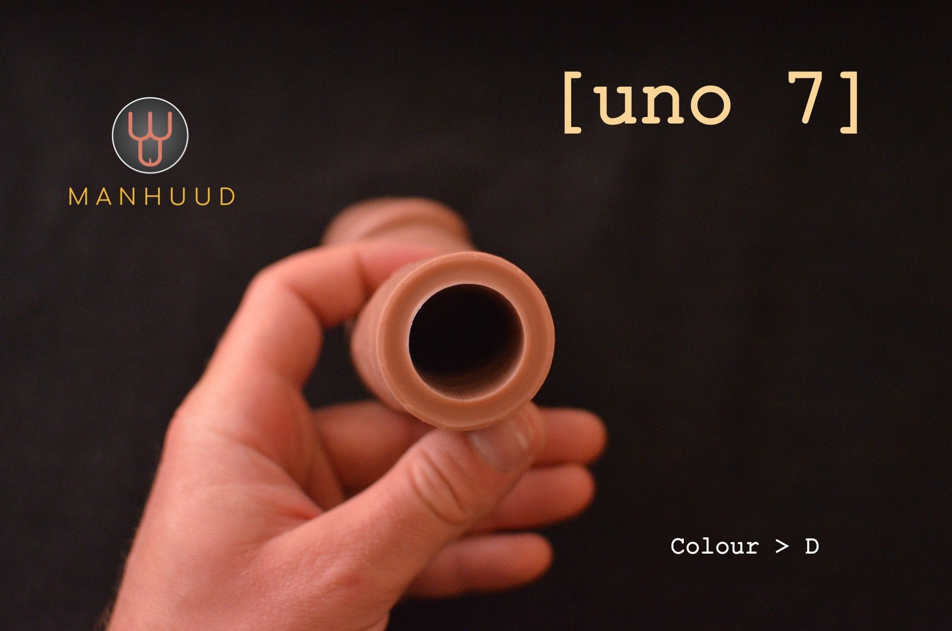 A hand holding a MANHUUD "uno 7" silicone penis sleeve, showing the open end