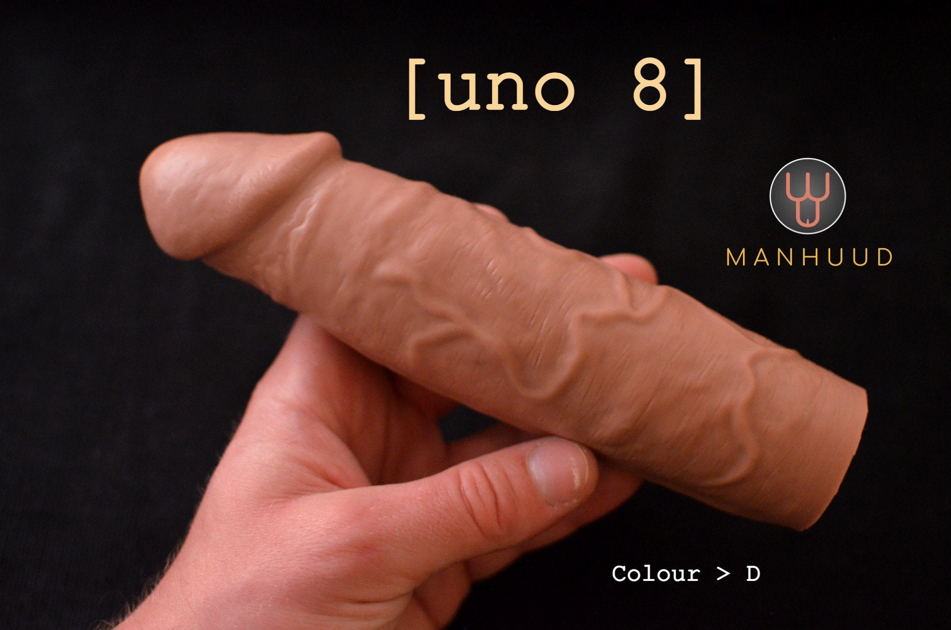 A hand holding a brown MANHUUD "uno 8" silicone penis sleeve