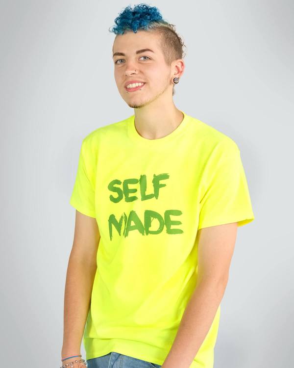 Person wearing yellow t-shirt over binder with 'self made' slogan