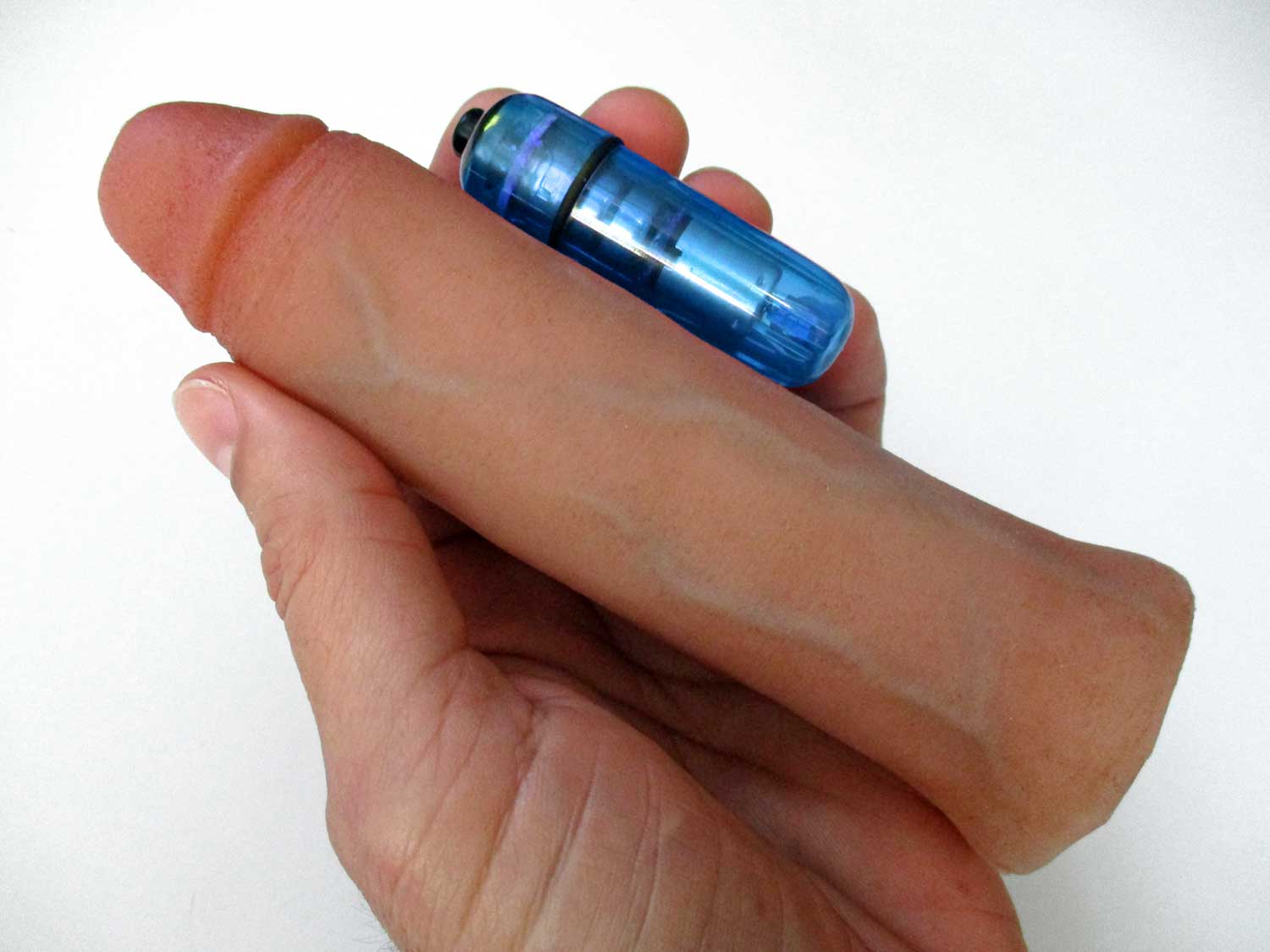 A hand holding a realistic, flesh-toned silicone dildo alongside a blue vibrating bullet