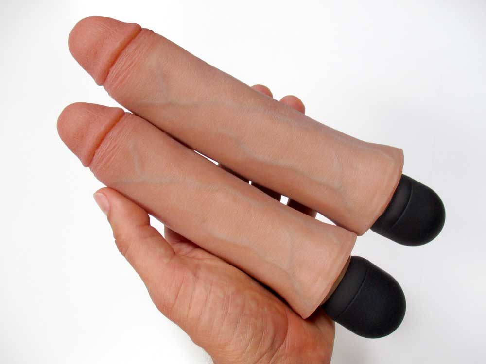 A hand holding two realistic, flesh-toned silicone dildos with black bases